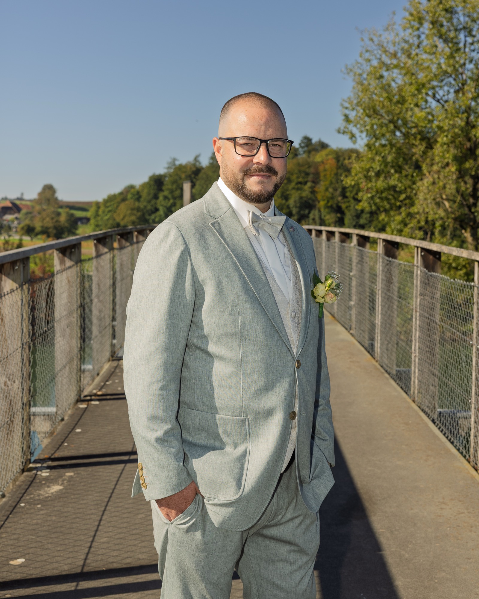 Silas im hellgrauen Anzug auf der Brücke